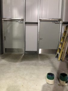 Two grey doors separated by a wall