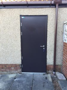Black steel door outside a rendered building
